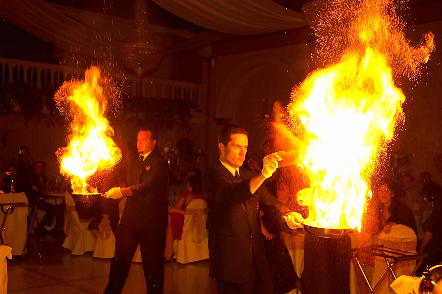 Spectacular wedding photograph of waiters preparing cherry flambe dessert with huge flames at The Olympia